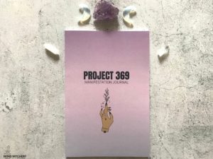 Project 369 Manifestation Journal with a black woman's hand manifesting